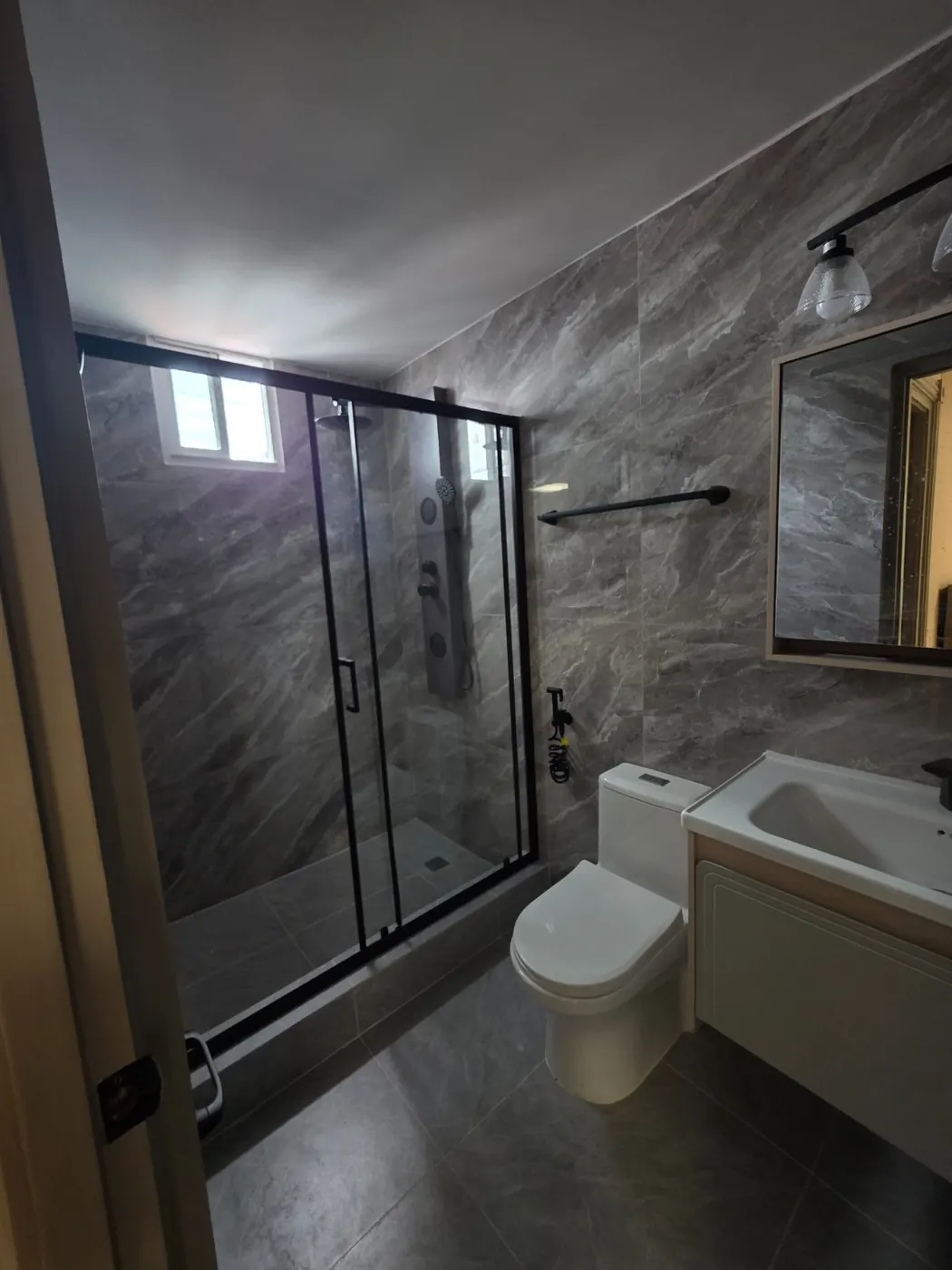 Baño en mármol oscuro con marcos negros por A&D Arquitectura
